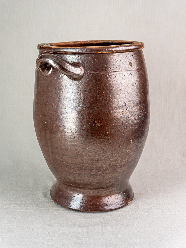 Large French brown salt-glazed stoneware jar with rounded body and single handle on neutral background.
