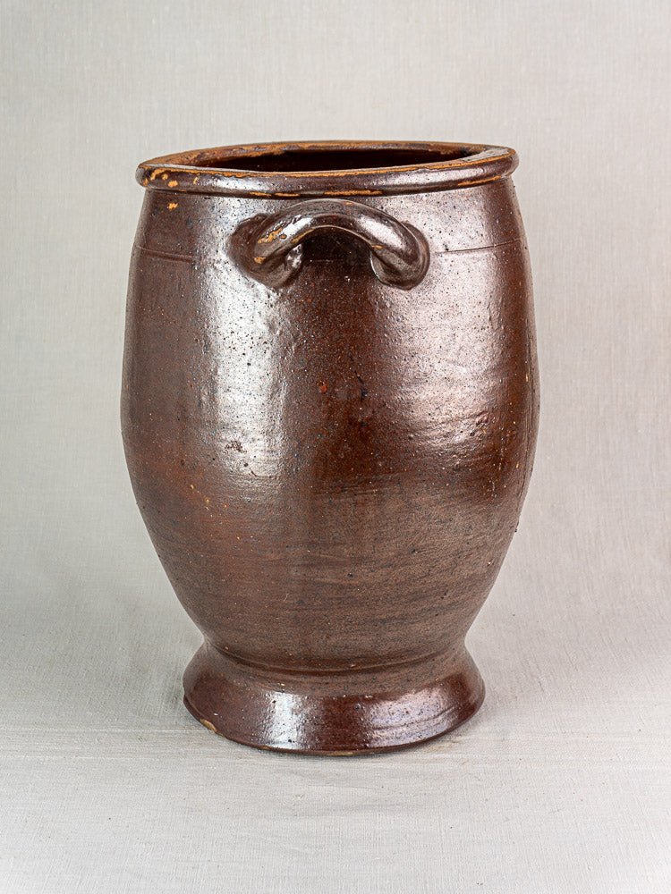 Large antique French pot à graisse with brown salt-glazed stoneware and loop handle on light gray background.
