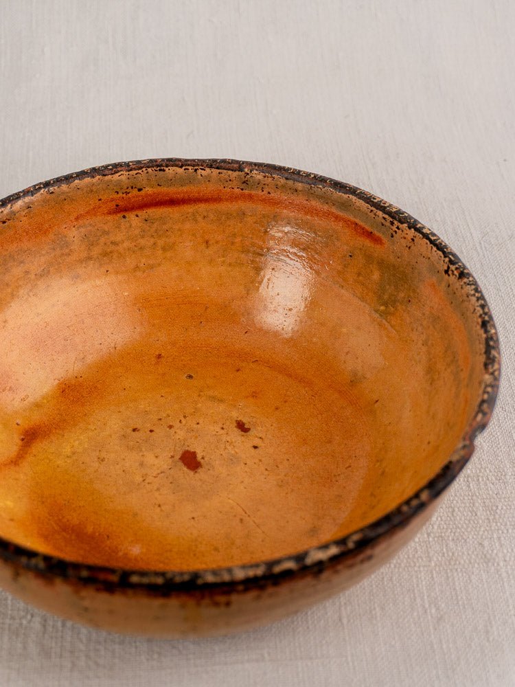 Antique French yellow glazed earthenware tian baking dish with rustic texture, on light surface.