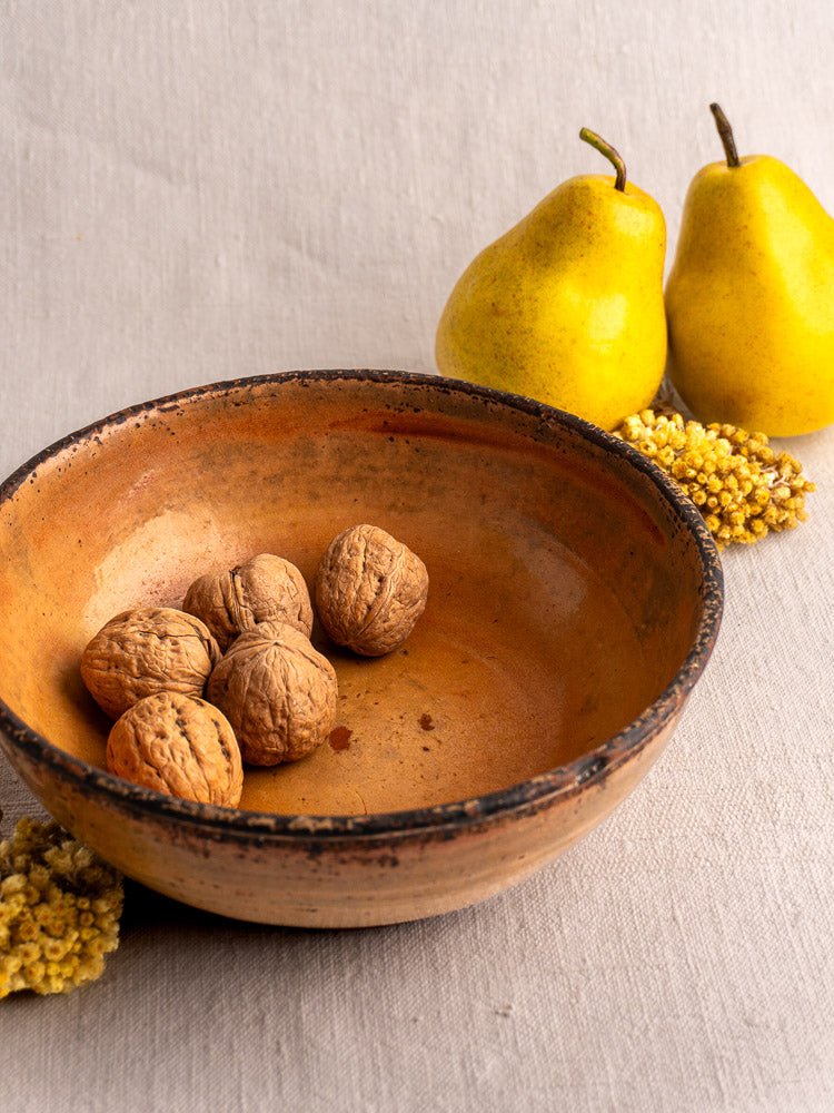 Antique French yellow-glazed earthenware Tian baking dish with walnuts, pears, and dried flowers.