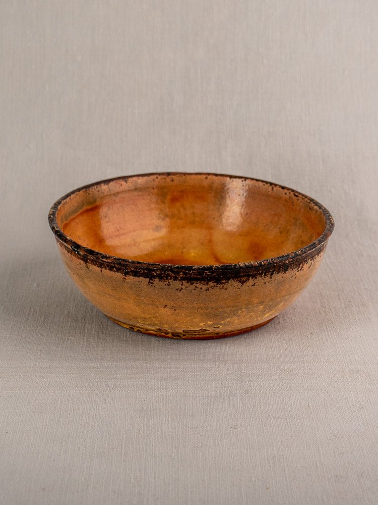 Antique French tian baking dish in yellow glazed earthenware with textured finish, neutral fabric backdrop.