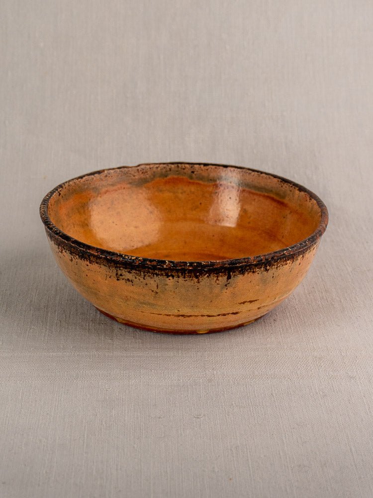 Antique French yellow-glazed earthenware Tian baking dish on a light gray textured surface.