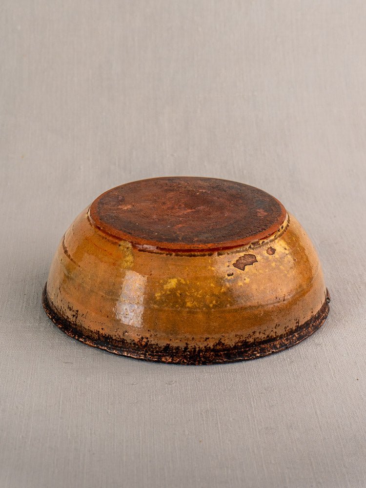 Antique French tian baking dish in yellow glazed earthenware, base exposed on gray fabric.