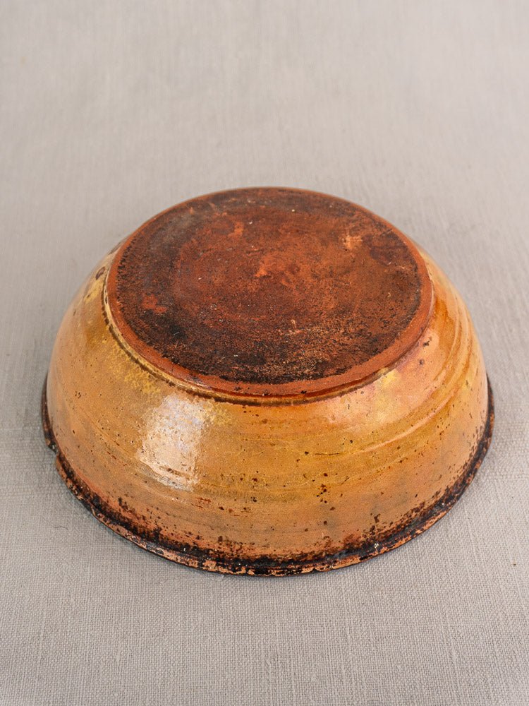 Late 19th century French Tian baking dish in yellow glazed earthenware, upside down on gray fabric.