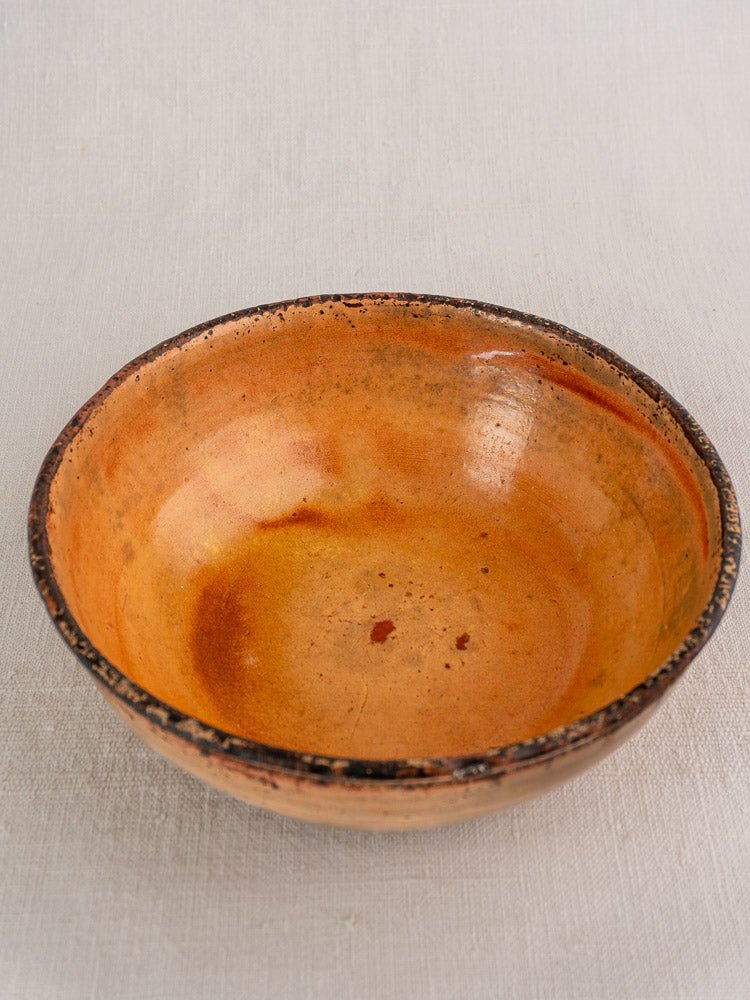 Antique French Tian baking dish in yellow glazed earthenware with orange-brown glaze on textured surface.