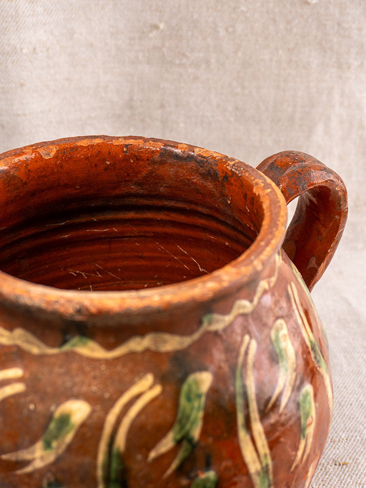 Early 19th century French terracotta pot, Jaspé slipware, single handle, rustic glaze, hand painted bird motif on fabric background.