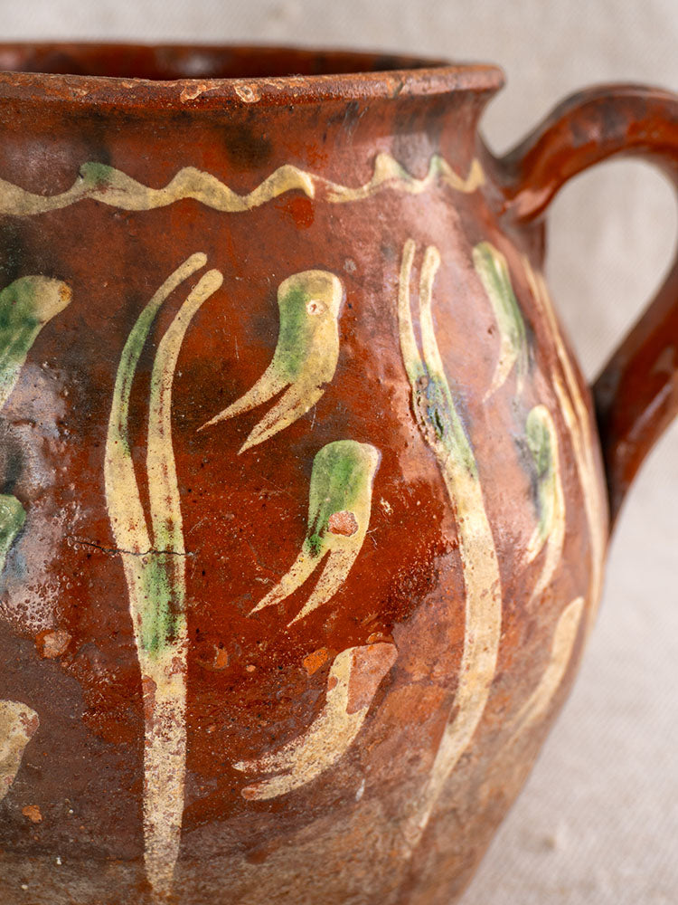 Early 19th century French terracotta pot with Jaspé décor, curved handle, bird and cream plant motifs.