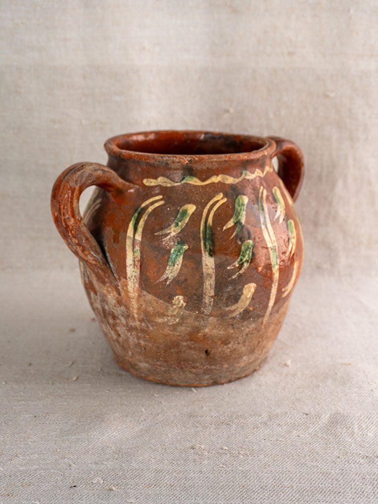 Early 19th century French terracotta pot with two handles, jaspé décor, green and yellow slipware on beige fabric.