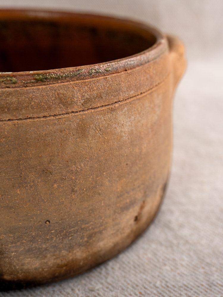 Antique French glazed terracotta hearth cooking pot with single handle and fire-darkened, rustic finish.