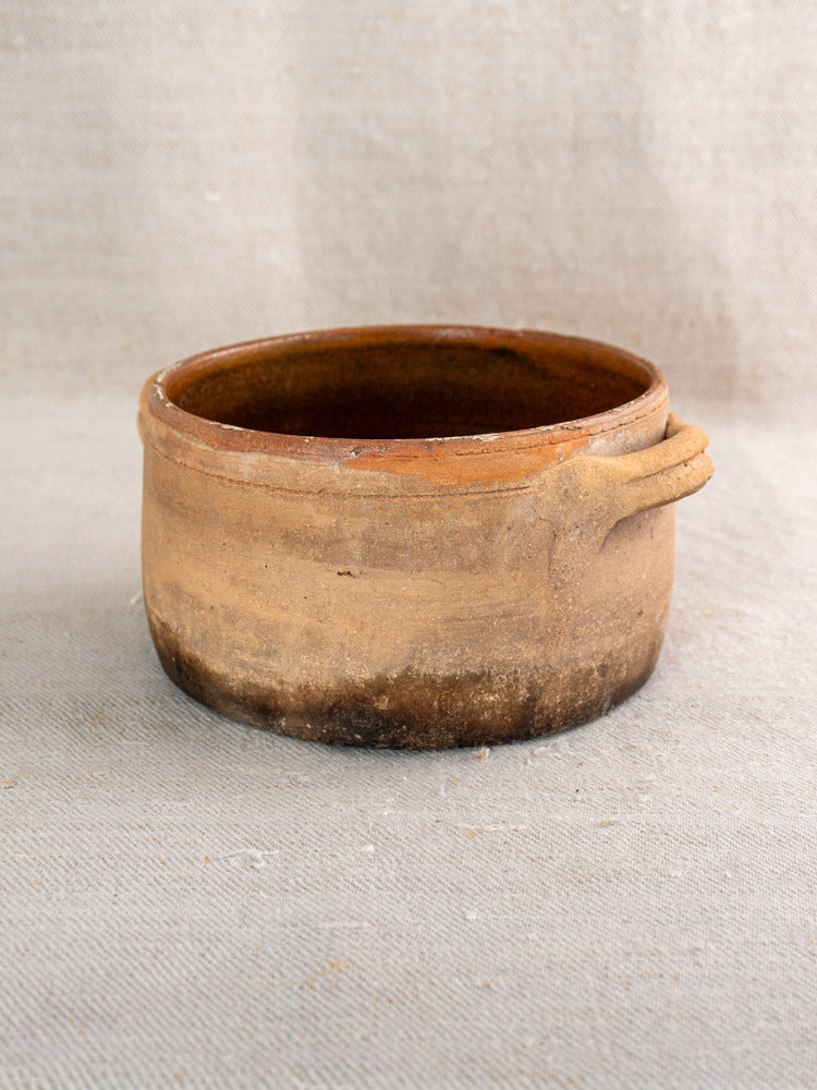 Antique French terracotta hearth cooking pot with handle, warm brown glaze and fire-darkened base.