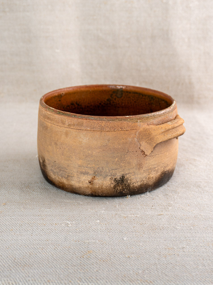 Antique French glazed terracotta cooking pot with rustic brown exterior and small side handle.