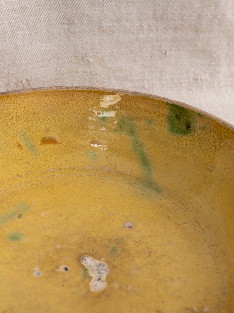 Antique French terracotta poêlon from Aubagne, late 18th century, yellow glaze with green spots, crackled finish on fabric backdrop.