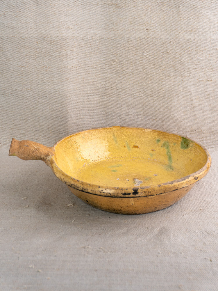 Antique French poêlon from Aubagne, late 18th century, yellow glazed terracotta with worn handle and traces of green inside.