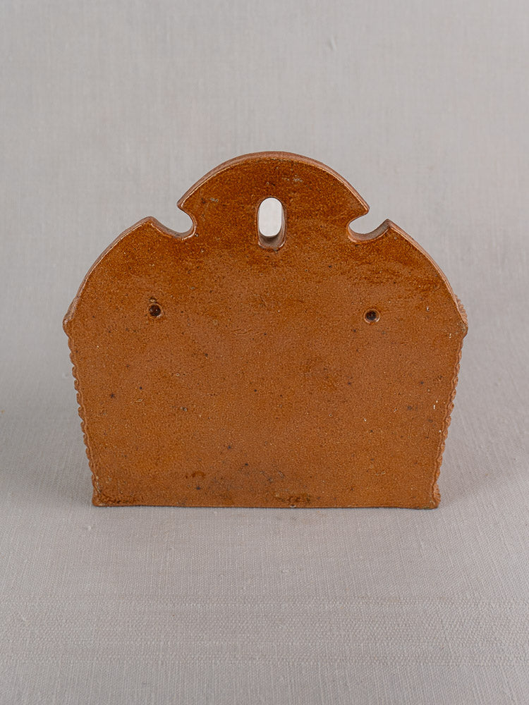 Antique French salt-glazed stoneware salt box, flat back with scalloped edge and hanging hole, on neutral background.