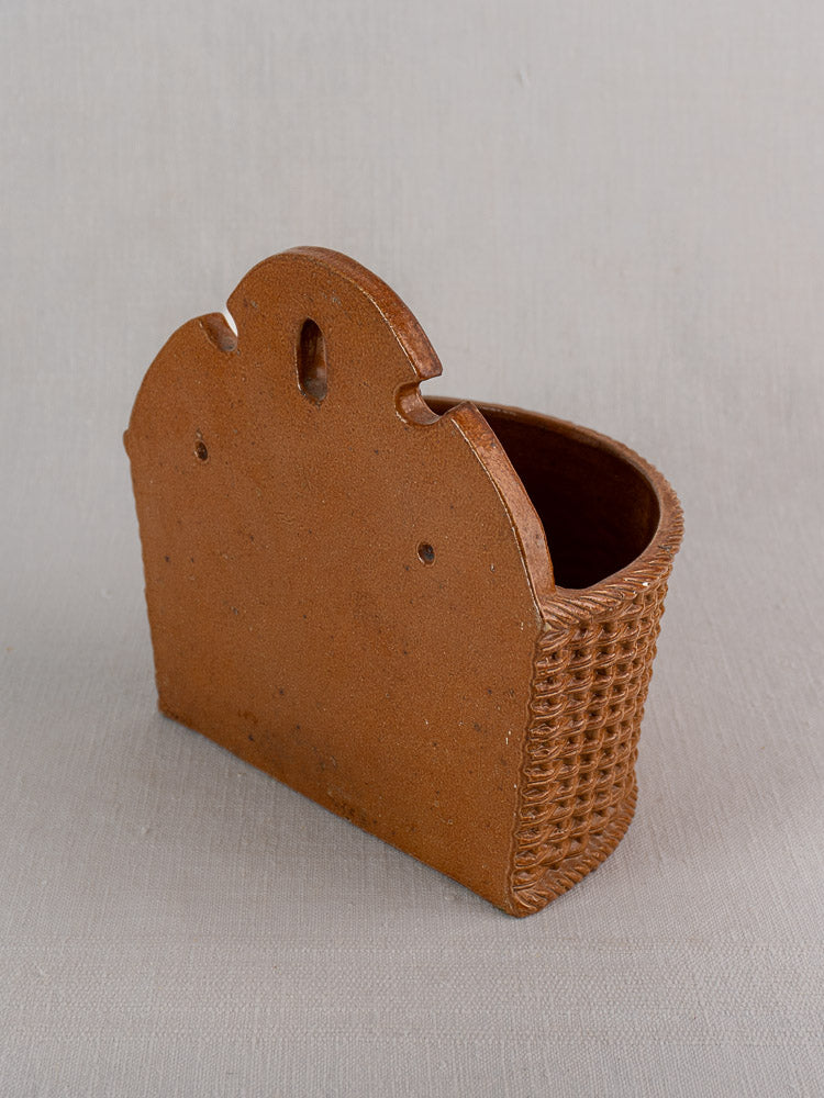 Antique French salt-glazed stoneware salt box, woven-textured sides, wide front opening, on light gray fabric background.