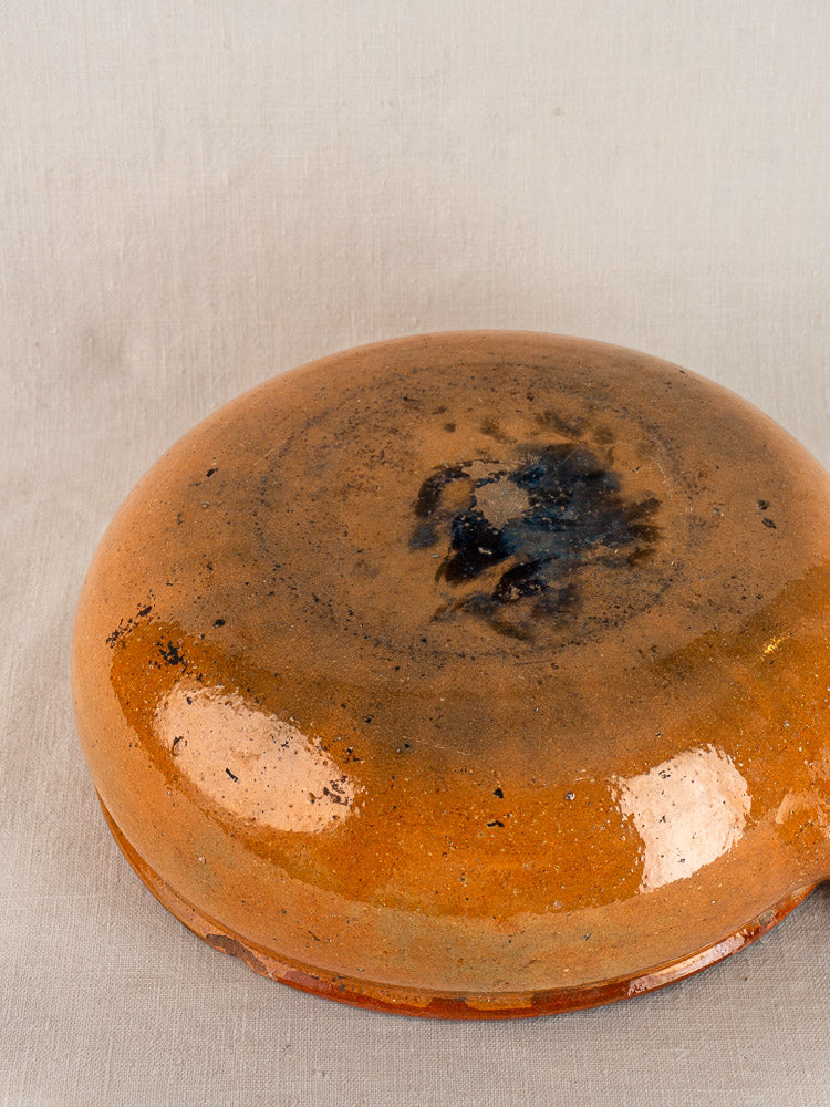 Antique French Vallauris poêlon, early 20th century, round shallow glazed terracotta with orange-brown finish, upside down.