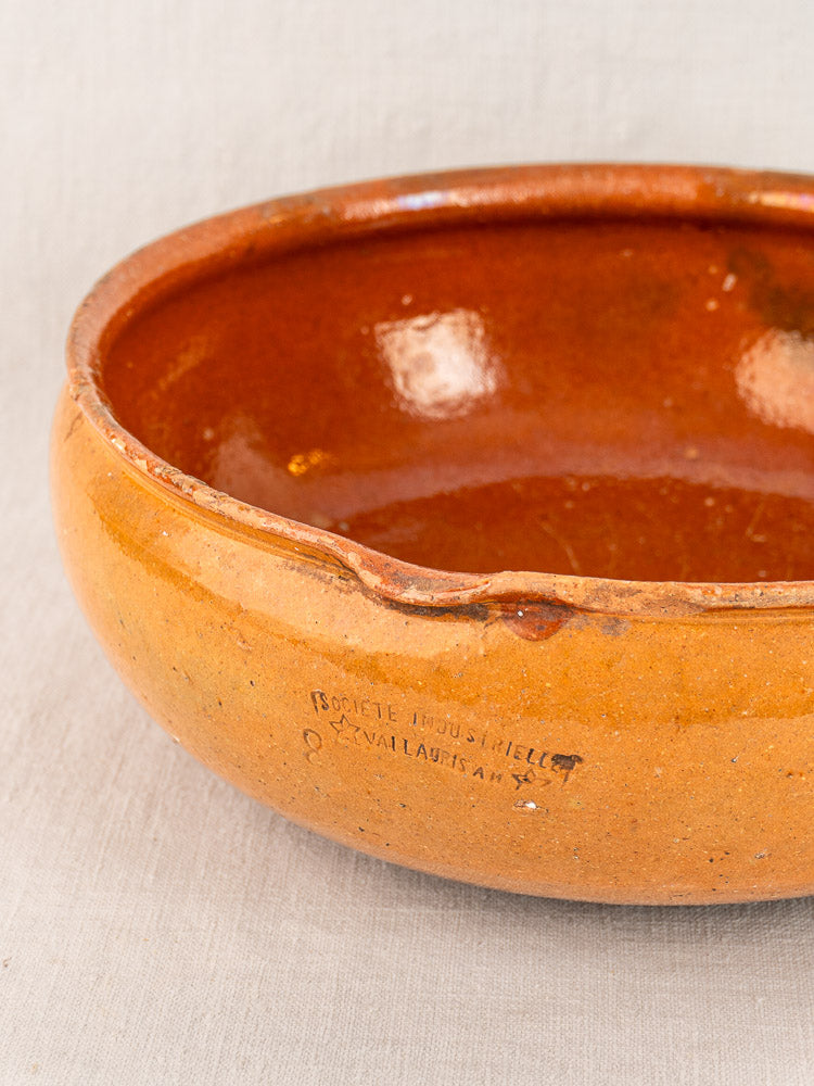 Antique French Vallauris poêlon, early 20th century glazed terracotta, matte orange-brown, on light gray fabric background.
