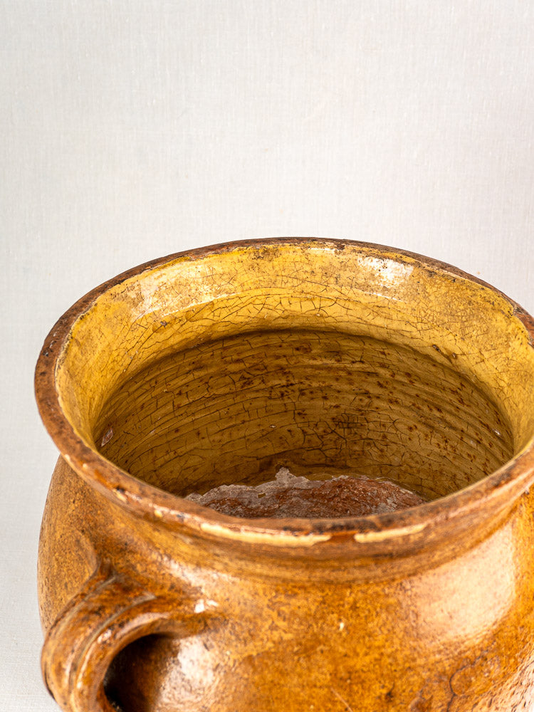 Antique French terracotta storage jar with rustic brown exterior, visible aging, and yellow glazed interior.