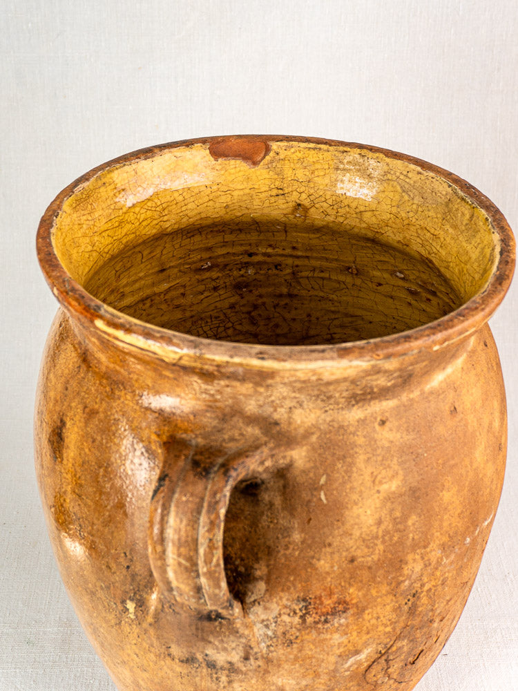 Antique French terracotta storage jar, 19th-century, wide mouth, single handle, yellow-glazed interior with age cracks.