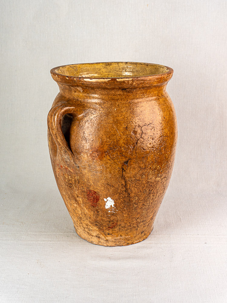 Antique French terracotta storage jar with yellow-glazed interior, rustic brown finish, single handle, aged patina.