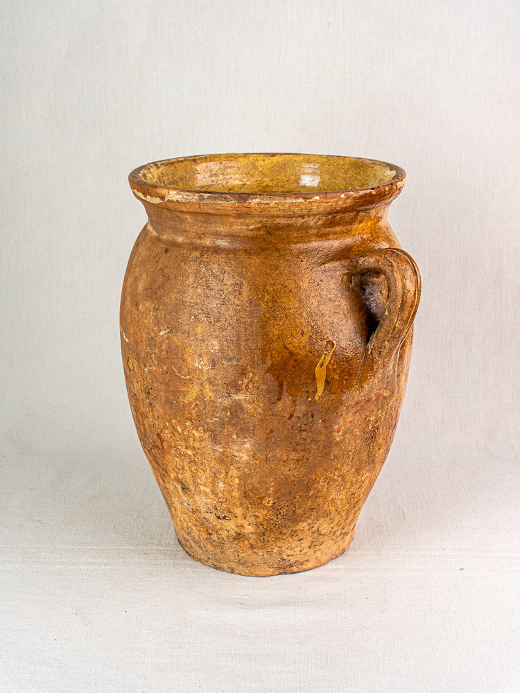 19th-century French terracotta storage jar with rustic brown clay, wide mouth, single handle, yellow glazed interior.