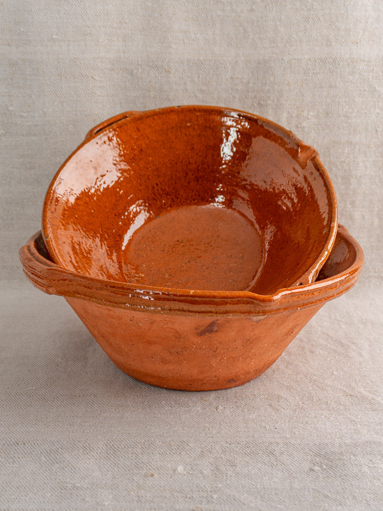 Pair of antique French Languedoc tian bowls in glazed earthenware, stacked on neutral fabric.