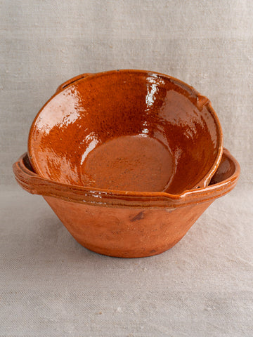 Pair of antique French Languedoc tian bowls in glazed earthenware, stacked on neutral fabric.