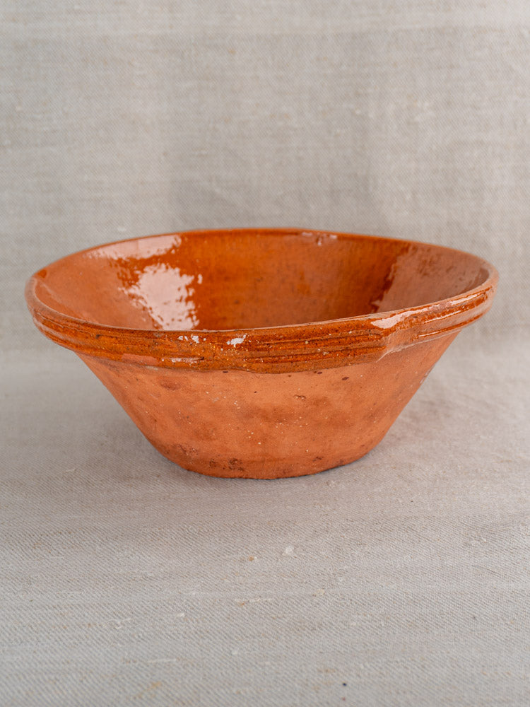 Pair of antique French Languedoc Tian bowls with glossy orange-brown glaze and broad rims on fabric.