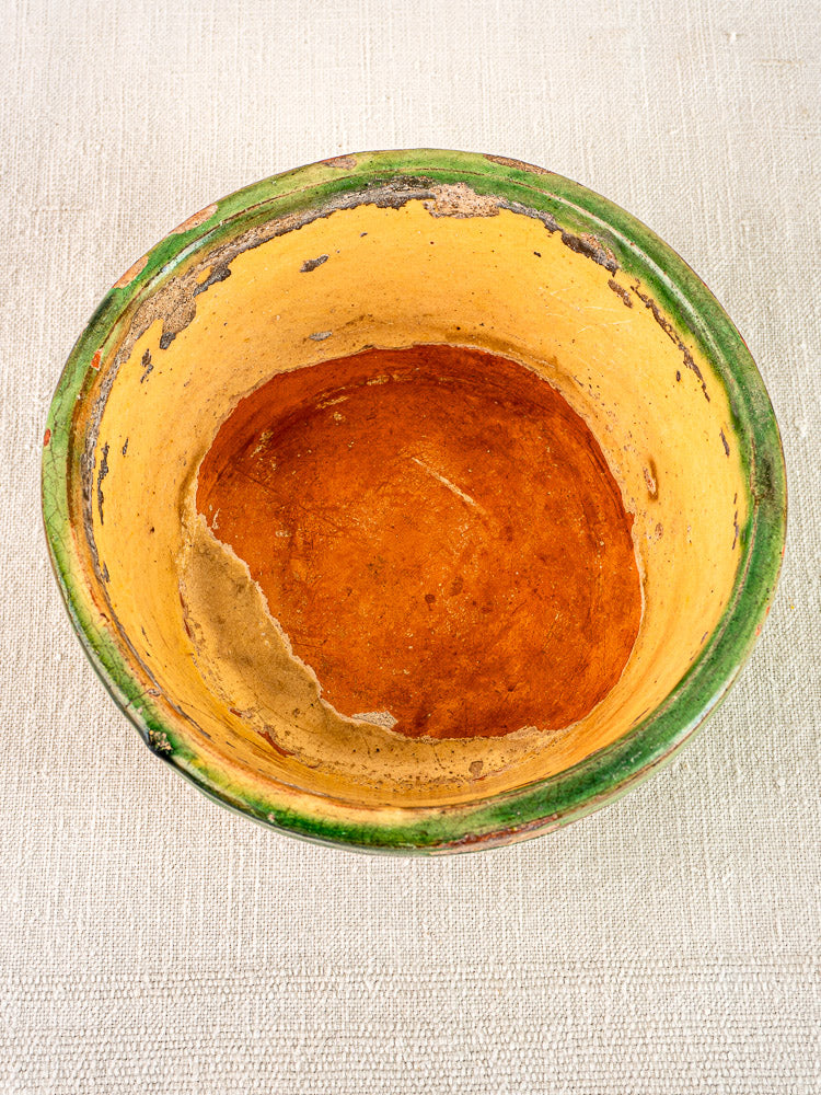 Antique French Tian bowl in Provencal terracotta with green rim, yellow glazed interior, worn and chipped.