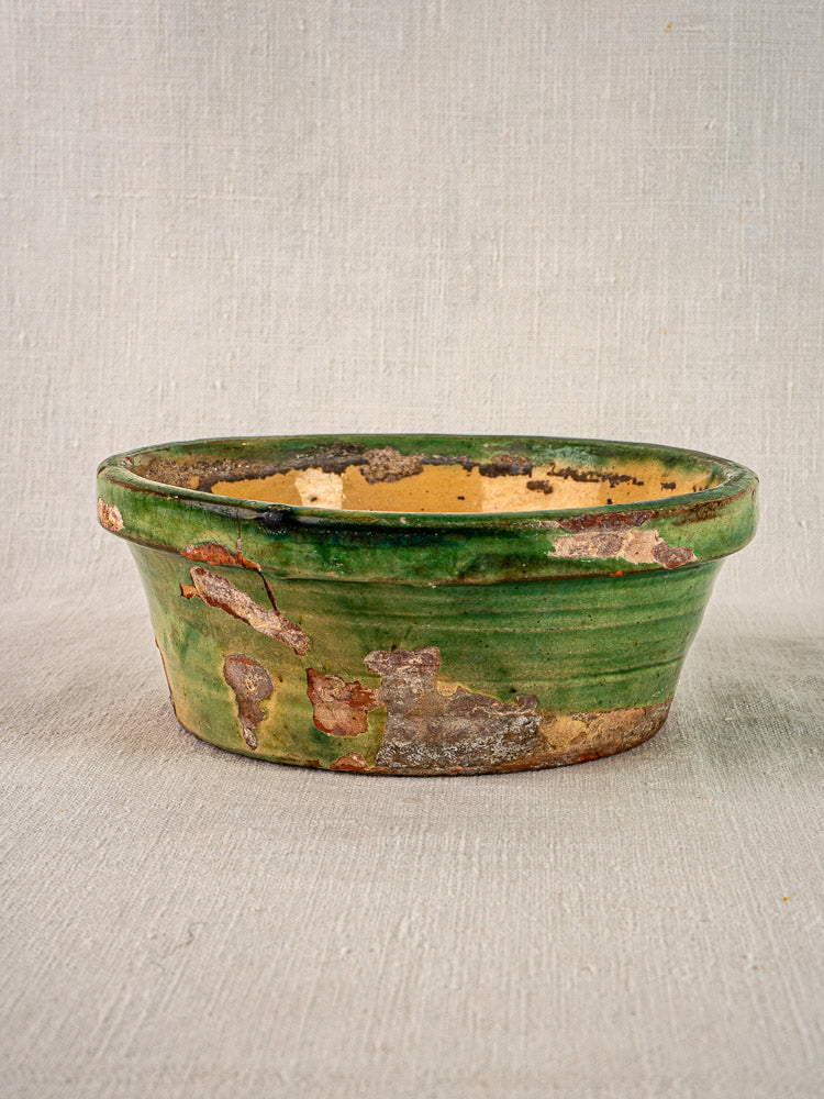 Antique French Tian bowl with Provençal terracotta, worn green and yellow glaze on light fabric.