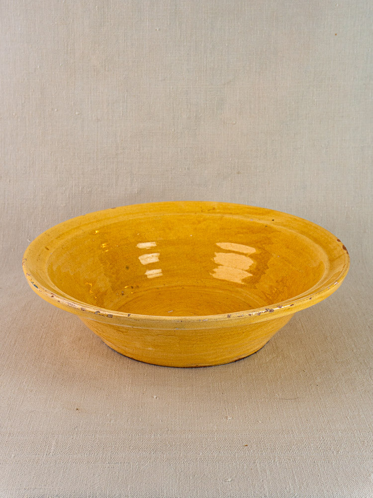 Antique French yellow glazed terracotta Tian bowl, circa 1900, on beige fabric surface.