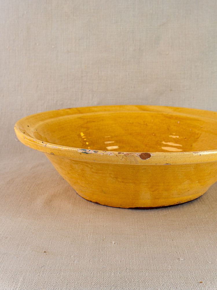 Antique French yellow glazed tian bowl in Provençal terracotta with ochre finish on neutral fabric.