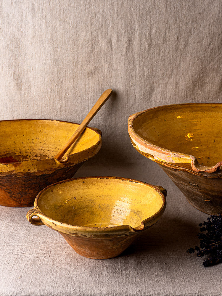 Antique Provençal yellow terracotta Tian bowls, rustic French pottery with handles and aged patina, on fabric.