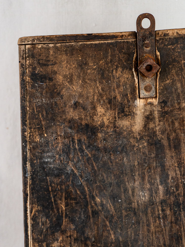 Weathered rusty iron latch on scratched brown surface from French Coupe-Tabac antique tobacco cutter.