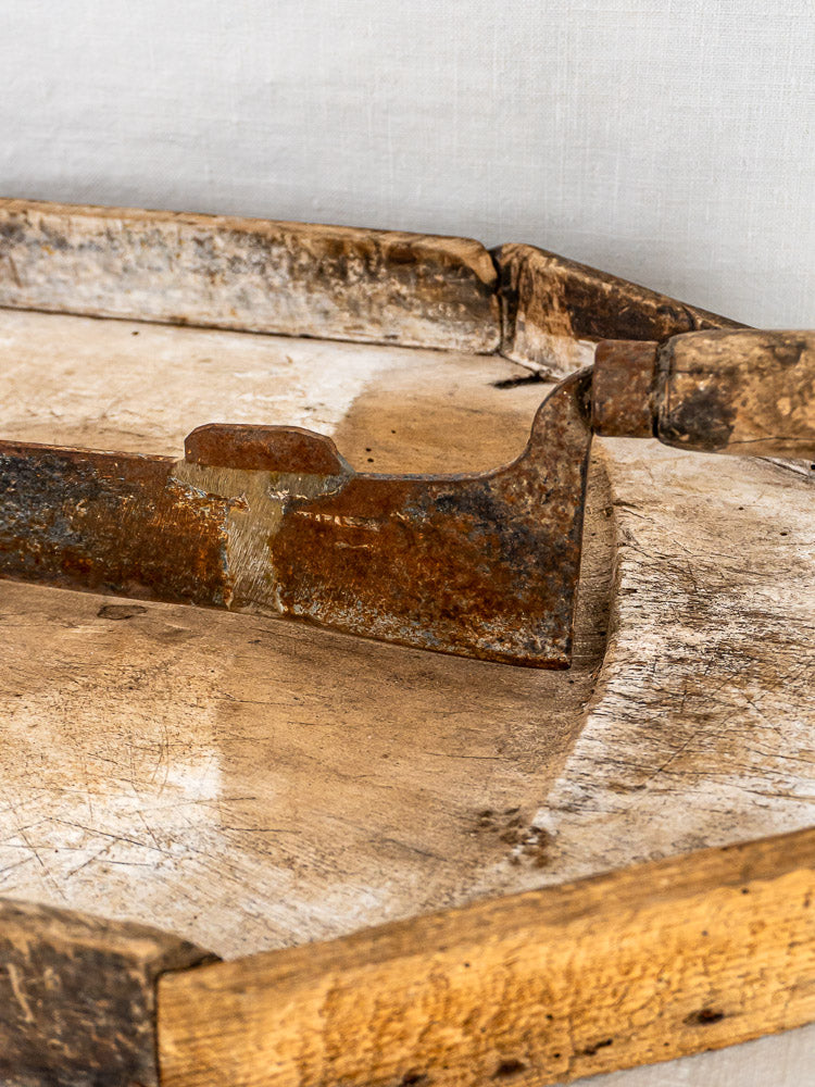 French antique wood and iron tobacco cutter displayed on a rustic wooden cutting board.