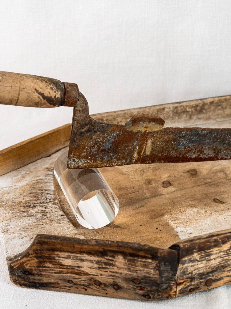 Antique French wood and iron tobacco cutter with worn handle on vintage wooden tray.