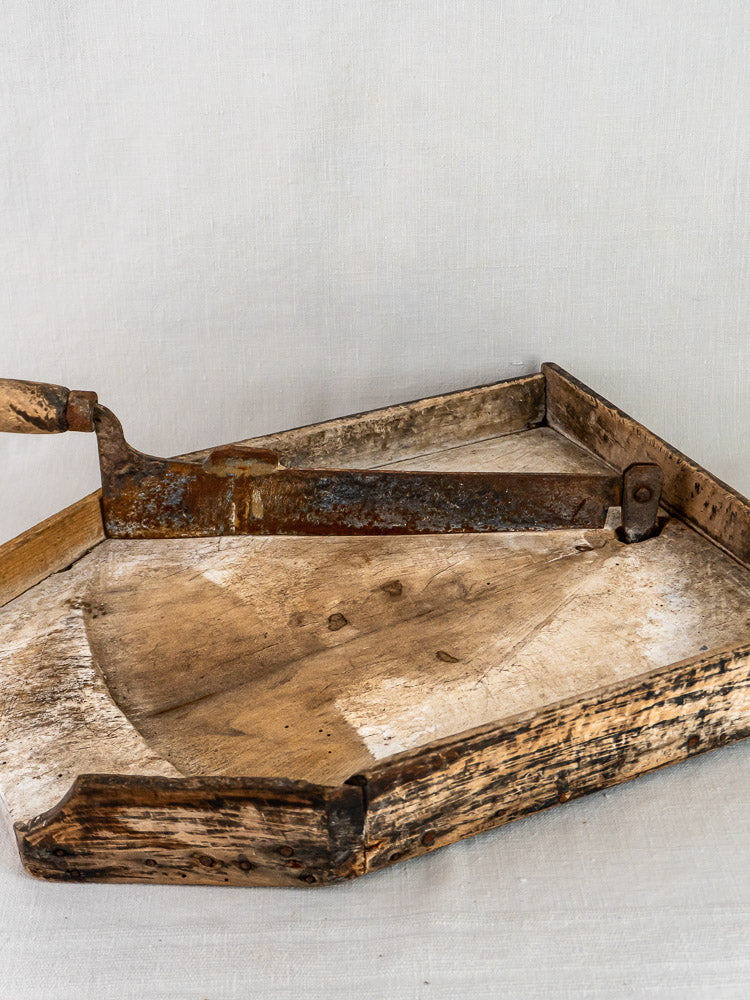 Antique French wood and iron Coupe-Tabac tobacco cutter with a curved, rusted blade on light fabric.