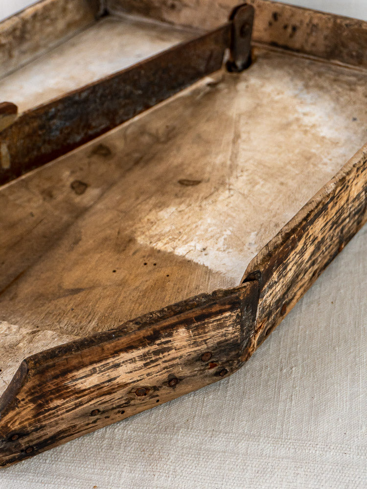 Antique French wood and iron tobacco cutter with weathered body and rusted handles on white surface.