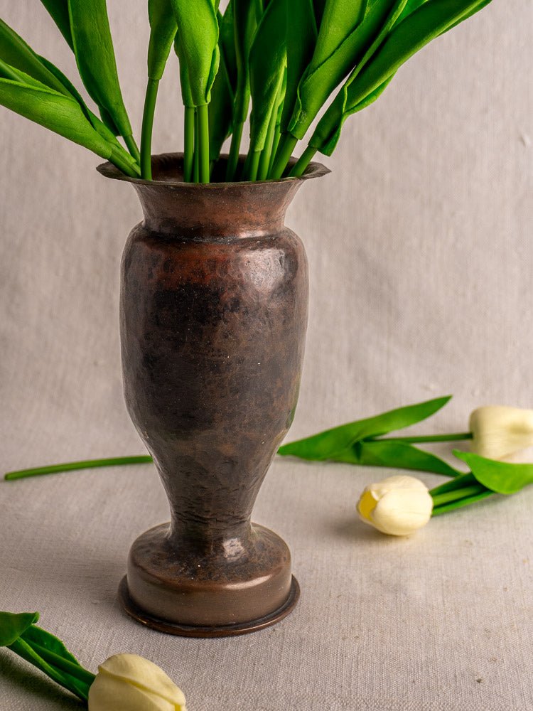 Antique French trench art vase from 1917 WWI shell casing with tulips, neutral fabric backdrop.