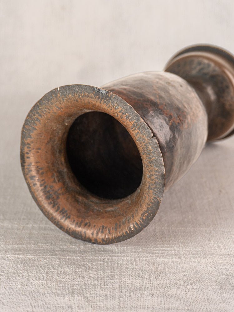 Antique French WWI trench art vase, 1917 shell casing with worn rim and aged patina on light textured surface.