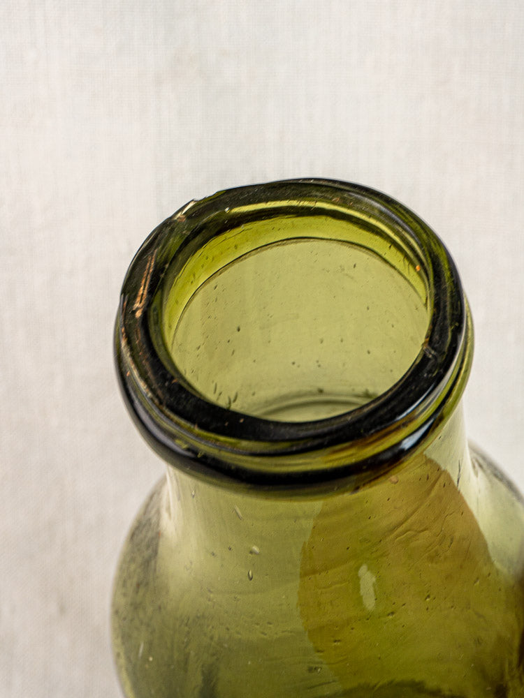 Antique French truffle bottle in hand blown olive glass, 19th century, chipped rim, neutral background.