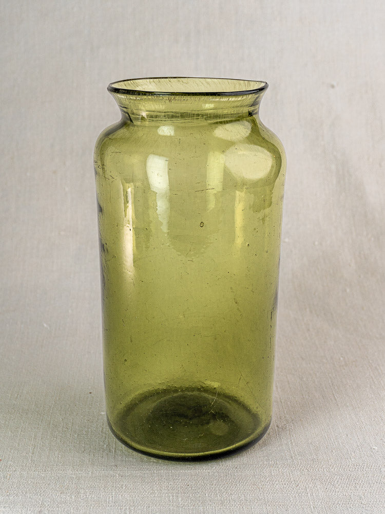 Antique French preserve jar, late 18th century hand-blown olive green glass on neutral textured surface.