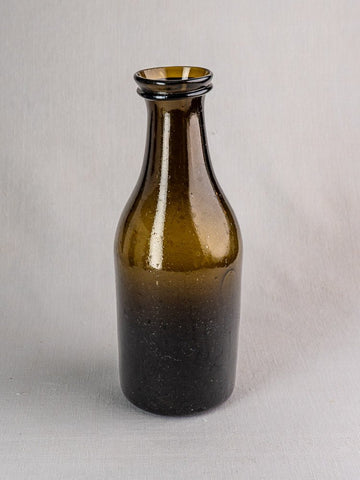 Antique French truffle jar, circa 1800, hand-blown olive glass with dark brown tone, on gray surface.