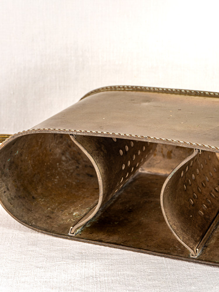 Vintage metal cheese grater with curved rectangular shape on light fabric background, classic kitchenware charm.