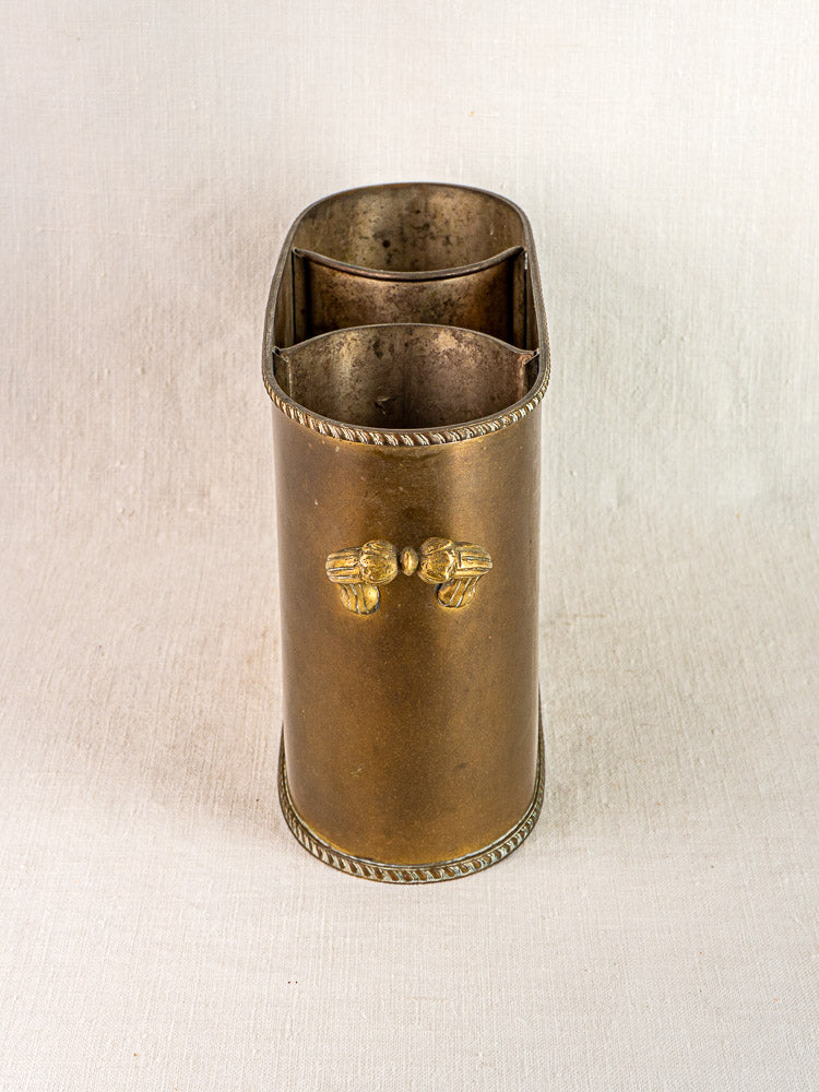 Vintage French brass double champagne cooler with ornate handles and rope details on neutral fabric.