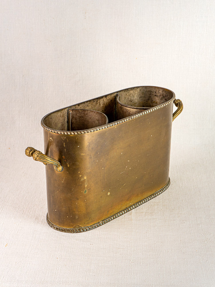 Antique French brass double champagne cooler with rope-style edges and twin handles on a light textured surface.