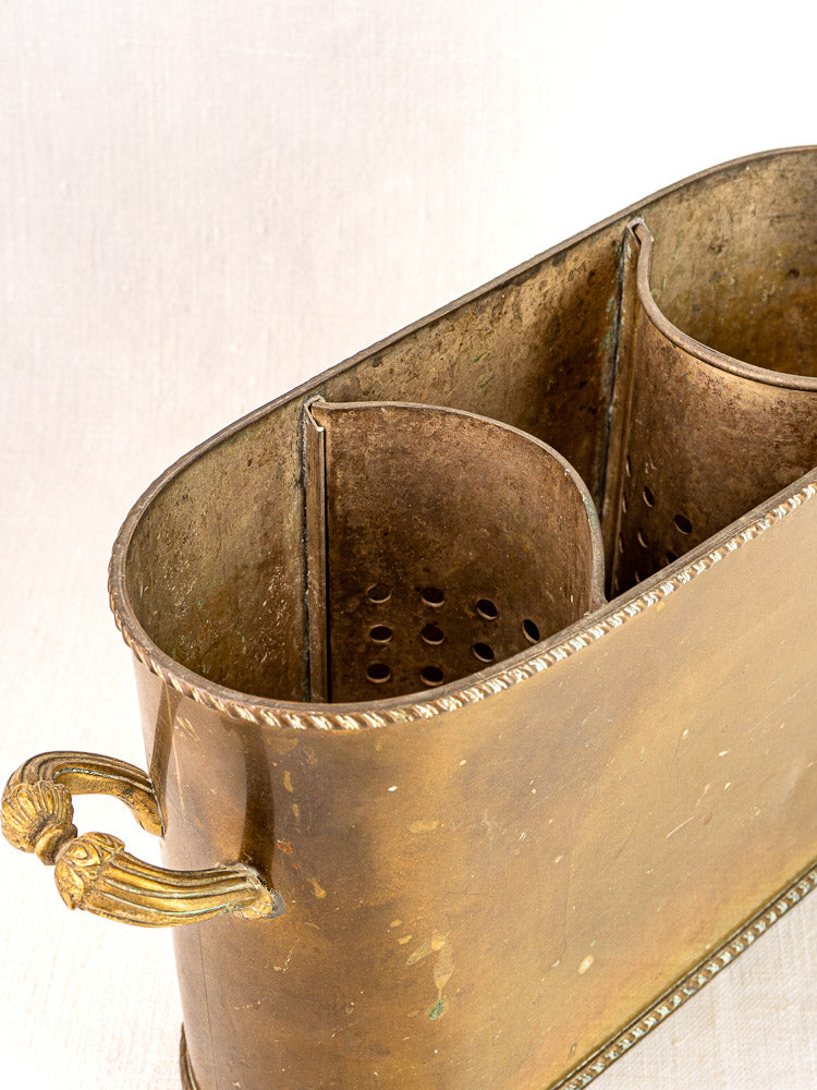 Antique French brass double champagne cooler with decorative handles and perforated dividers on a light background.