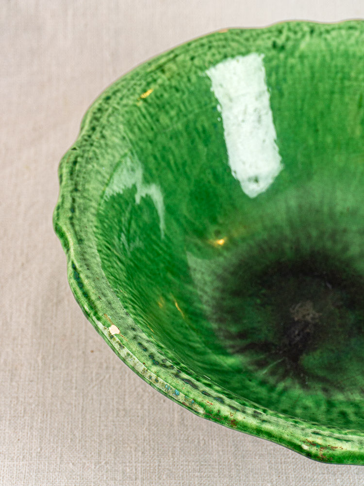 French Vallauris bowl by Foucard-Jourdan, green glaze, textured wavy rim, glossy finish, early 20th century on beige fabric.