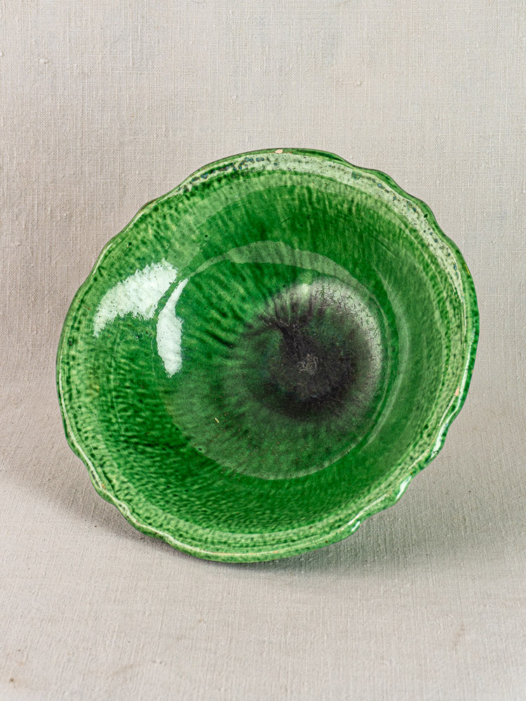 French Vallauris bowl by Foucard-Jourdan with scalloped rim, mottled green glaze, early 20th century, on light textured surface.