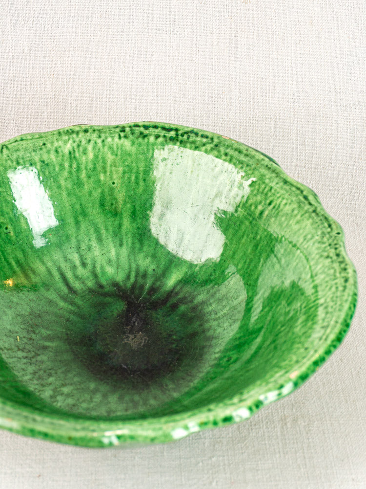 French Vallauris Bowl by Foucard-Jourdan with green glaze, scalloped edge, and glossy finish on light fabric background.
